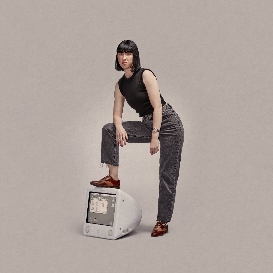 Lady standing on top of old-school iMac with built-in screen