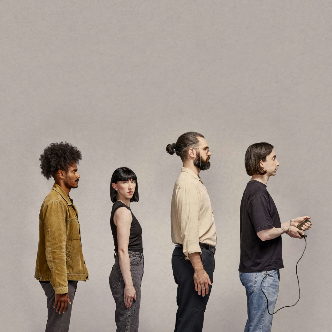 Four people standing in line, last has a controller
